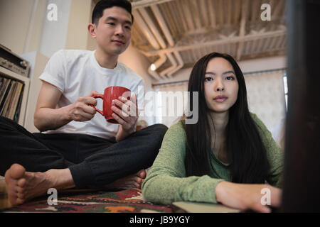 Couple using laptop while having coffee in living room at home Stock Photo