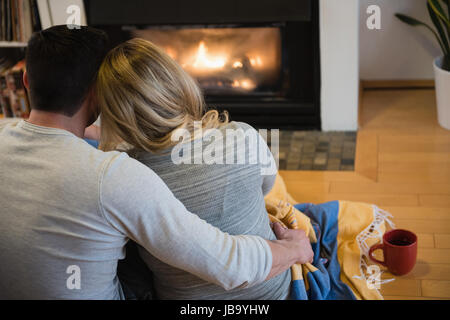 Rear view of couple relaxing in living room at home Stock Photo