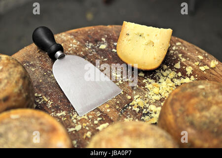 Special knife and famous italian cheese pecorino on small wooden table. Stock Photo