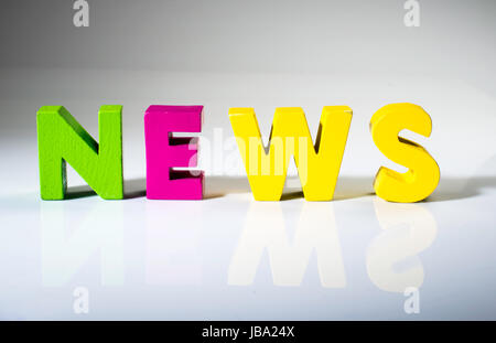 Multicolored text news made of wood. White background Stock Photo