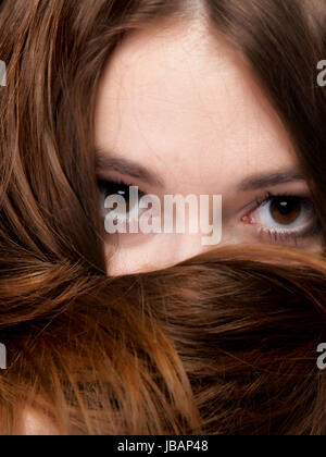 Close-up portrait of a beautiful woman covers the face by long brown hairs