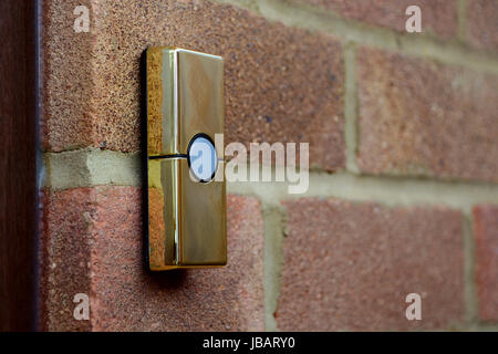 Gold or brass coloured doorbell on the brick wall of a house Stock Photo