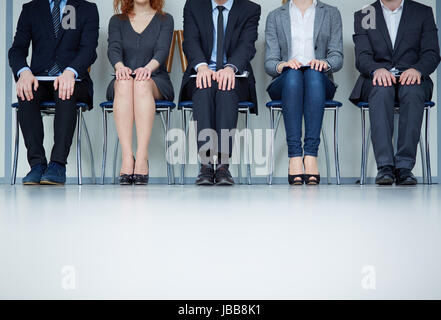 Several business people sitting on chairs in a row Stock Photo