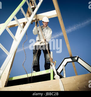 construction worker with ladder and winch on top of construction. Stock Photo