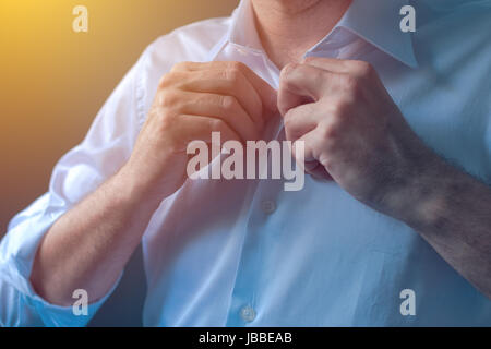 Businessman buttons white shirt with roll up tuck sleeves, getting ready for work day Stock Photo