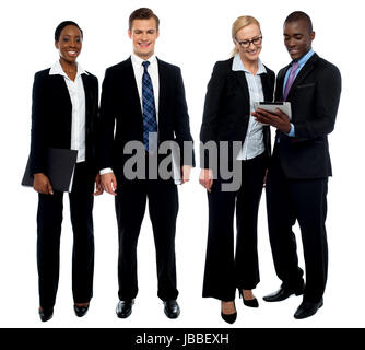 Corporate team of four posing with tablet pc. One team using tablet and other members facing camera Stock Photo