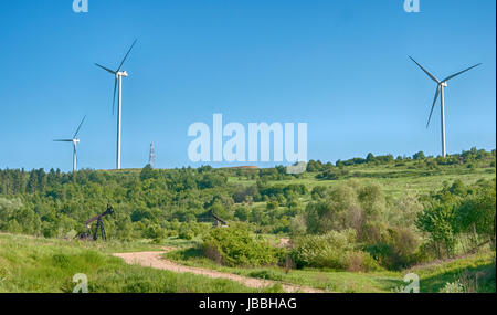 New energy era is coming. An old oil pump jack in front of modern wind turbines Stock Photo