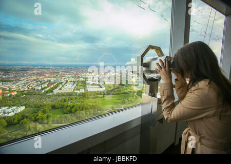 MUNICH, GERMANY - MAY 6, 2017 : A woman looking at the cityscape through the binoculars at the observation platform of the Olympic Tower in the Olympi Stock Photo