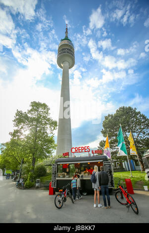 MUNICH, GERMANY - MAY 6, 2017 : People at a food stand with pancakes and a low angle view of the Olympic Tower in the Olympic Park in Munich, Germany. Stock Photo