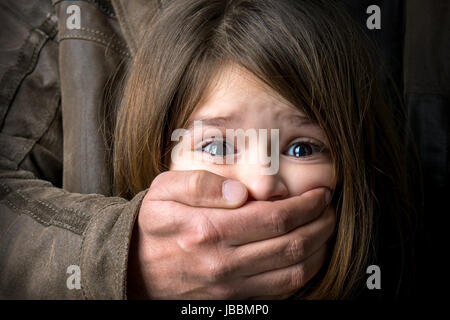 Scared young girl with an adult man's hand covering her mouth Stock Photo