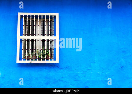 A blue colonial wall with a white window in the historic La Candelaria neighborhood in Bogota, Colombia Stock Photo