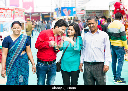 happy Indian Family Eating Ice Candy Sister Feeding On Brother Fair In Suraj kund Stock Photo