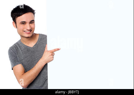 Cheerful guy pointing towards copy space area of whiteboard Stock Photo