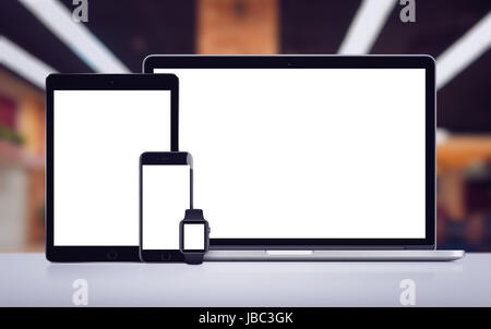 Laptop tablet smartphone and smartwatch mockup with white screens on the desk in office space Stock Photo