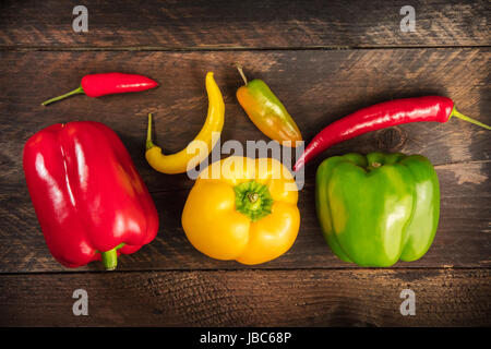 An overhead photo of vibrant colourful fresh bell peppers and chillies on a dark rustic background texture Stock Photo
