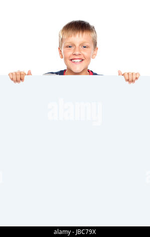 Young boy hiding behind big whiteboard ad. Business concept Stock Photo