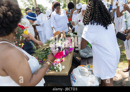 Charleston, South Carolina, USA. 10th June, 2017. Descendants of enslaved Africans brought to Charleston in the Middle Passage select flowers to toss in the ocean to honor their relatives lost during a remembrance ceremony at Fort Moutrie National Monument June 10, 2017 in Sullivan's Island, South Carolina. The Middle Passage refers to the triangular trade in which millions of Africans were shipped to the New World as part of the Atlantic slave trade. An estimated 15% of the Africans died at sea and considerably more in the process of capturing and transporting. Credit: Planetpix/Alamy Live Ne Stock Photo