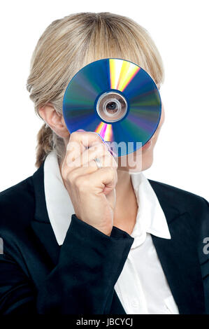 Young corporate lady looking at you through compact disc hole and smiling. Stock Photo