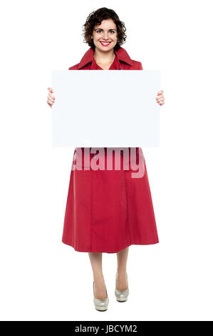 Full length portrait of a pretty young model posing with blank ad board. Stock Photo
