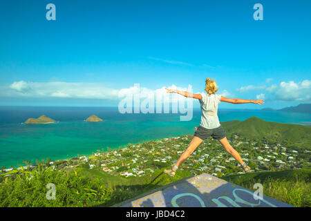 Lanikai Pillbox Hike. Hawaiian hiking enjoying. Joyful carefree hiker jumping. Happy woman celebrates one of most spectacular Oahu hiking trails in Ha Stock Photo