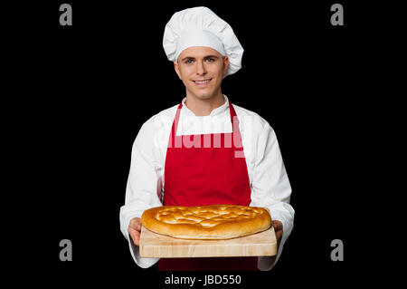 Isolated chef holding bread, black background. Stock Photo