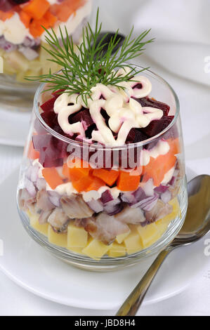 Salad of chopped herring with onions, potatoes, beets, carrots, seasoned with yogurt sauce in a glass Stock Photo