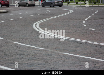 curved road made from a cobblestone stone blocks with marking in historical city centre Stock Photo