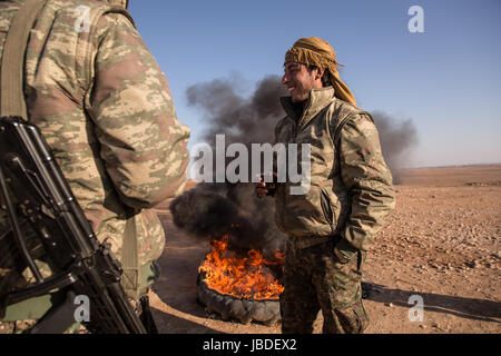 Chris Huby / Le Pictorium -  Syria / Rojava - Wrath of the Euphrates -  19/12/2016  -  Rojava  -  SYRIA ROJAVA / QALLAT JABBER village / The night before, this village was  liberated from ISIS. A YPG soldier taking tea in front of a big fire. The village is a few km from Raqqa. Stock Photo