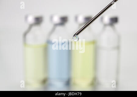 Needle of syringe with ampules on white blurred background Stock Photo