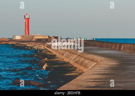 Red lighthouse on breakwater jetty at Baltic sea