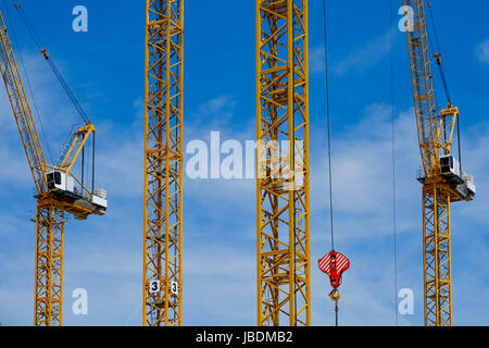 many yellow construction cranes on blue sky backgrounds Stock Photo