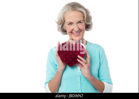 Senior woman holding heart shaped valentine gift Stock Photo