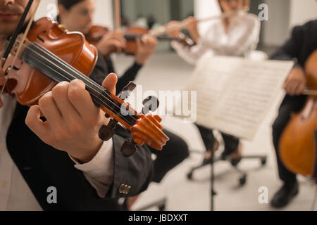 Violinist performing on stage with classical music symphony orchestra, hands close up, selective focus, unrecognizable people Stock Photo