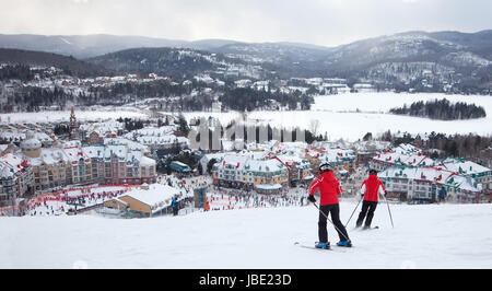 Mont-Tremblant, Canada - February 9, 2014: Skiers and snowboarders are sliding down the main slope at Mont-Tremblant. Mont-Tremblant Ski Resort is acknowledged by most industry experts as being the best ski resort in Eastern North America. Stock Photo