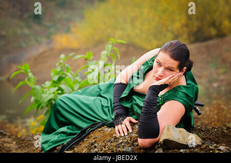 Erwachsene Frau im eleganten Abendkleid liegt im Steinbruch und wartet. Stock Photo