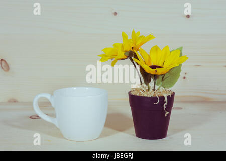 Sunflower in a Flowerpot and a cup of coffee On a wooden background Stock Photo