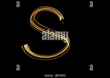 Gold letter S, Light Painting Photography, alphabet series, against a black background Stock Photo