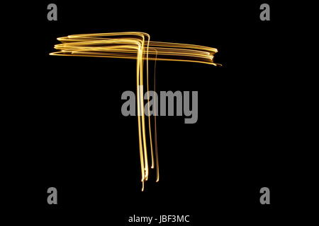 Gold letter T, Light Painting Photography, alphabet series, against a black background Stock Photo