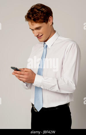 Smiling salesman on his cellphone with colleague behind him against a ...
