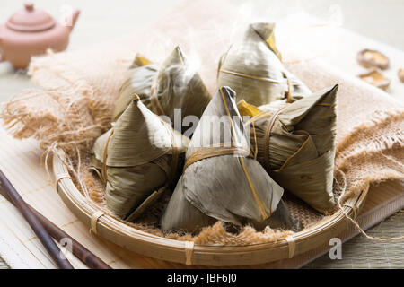 Asian Chinese rice dumplings on basket, tea at background. Stock Photo