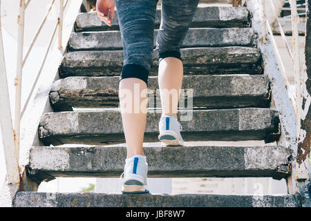 Slim girl in sneakers and sportswear climbing stairs, close-up, low angle shooting Stock Photo