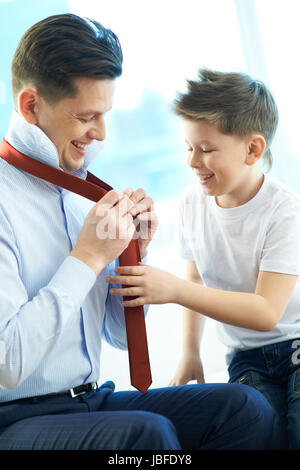 Photo of happy boy looking at his father tying necktie Stock Photo