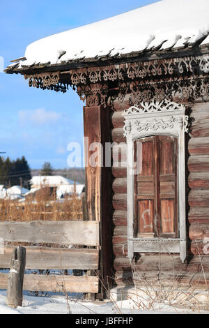 Window on a weathered wooden wall.  Rural landscape and Architecture of old wooden house, Sunny day in winter. Stock Photo