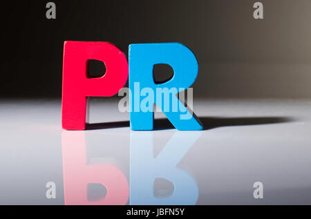 Multicolored text PR made of wood. White background Stock Photo