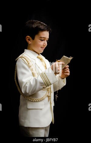 A young boy with rosary and prayer book celebrating his First Holy Communion Stock Photo