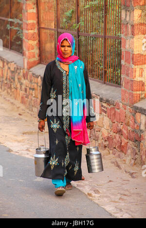 Local woman carrying milk jugs in the street of Fatehpur Sikri, Uttar Pradesh, India. The city was founded in 1569 by the Mughal Emperor Akbar, and se Stock Photo