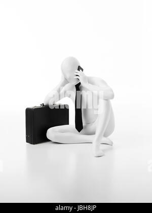 Faceless businessman dressed in white leaning on black briefcase, talking on the phone Stock Photo