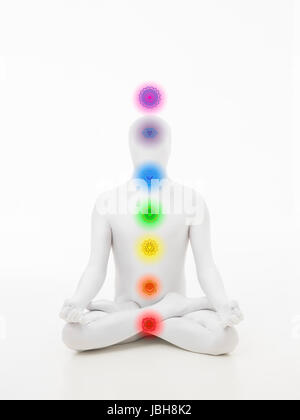 faceless man dressed in white sitting in yoga lotus position with chakra colored graphics Stock Photo