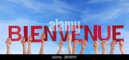 Many Hands Holding the French Word Bienvenue in the Sky which means Welcome Stock Photo