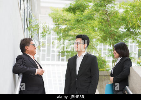 Asian business team chatting during business break outside office. Stock Photo